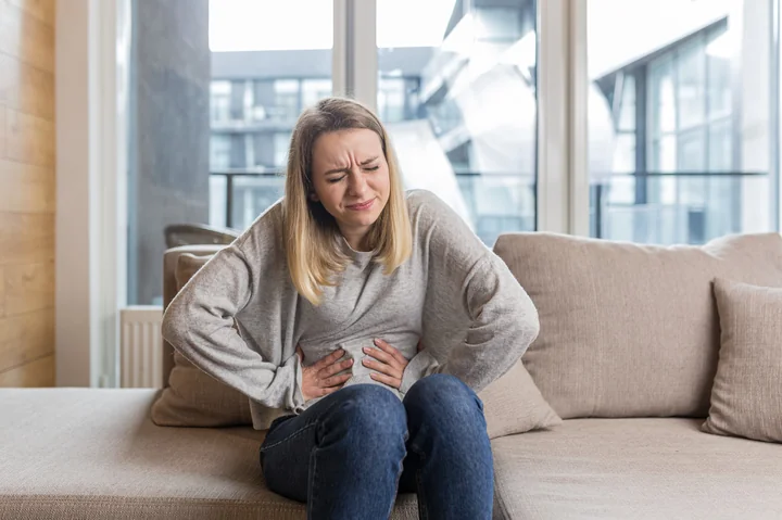 Obraz przedstawia kobietę, która trzyma się za brzuch